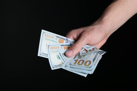Man with dollar banknotes on black background, closeup