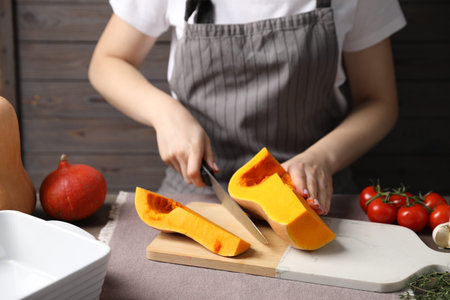 Woman cutting fresh pumpkin at table, closeup