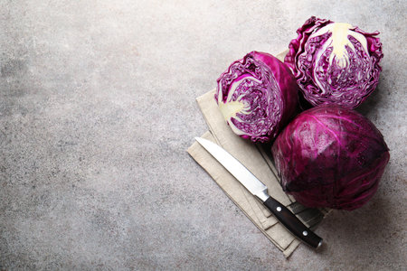 Whole and cut red cabbages with knife on gray table, flat lay. Space for textの写真素材