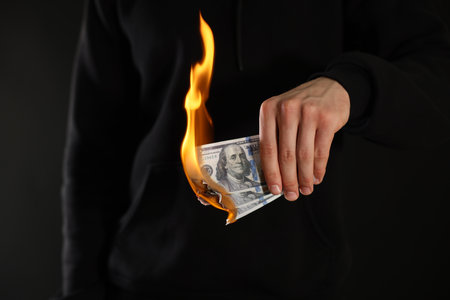 Man burning dollar banknotes on black background, closeupの写真素材