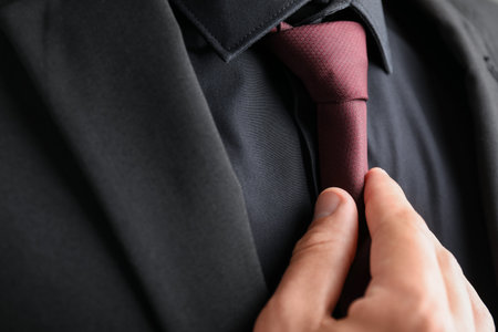 Man in suit adjusting his necktie, closeupの写真素材