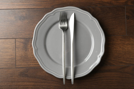 Ceramic plate and cutlery on wooden table, top viewの写真素材
