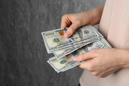 Alimony. Woman with dollar banknotes on gray background, closeup. Space for text