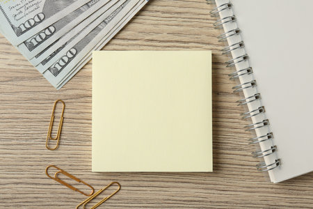 Alimony. Sticky notes, money, notebook and paper clips on wooden table, flat layの写真素材