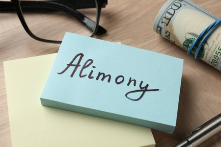 Notes with word Alimony, money, pen and glasses on wooden table, closeupの写真素材