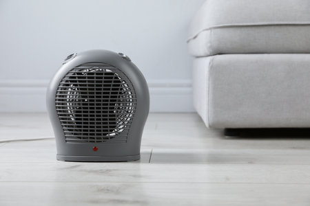 Electric fan heater on light wooden floor indoors. Space for textの写真素材