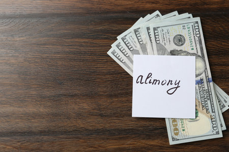 Note with word Alimony and money on wooden table, top view. Space for textの写真素材