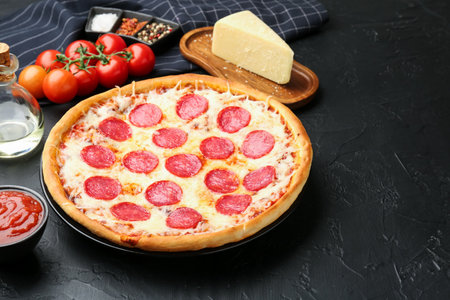 Delicious pepperoni pizza and ingredients on black table, closeupの写真素材