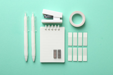 White stapler and other stationery on turquoise background, flat layの写真素材