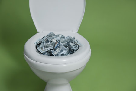 Dollar banknotes in toilet bowl on green background, closeupの写真素材