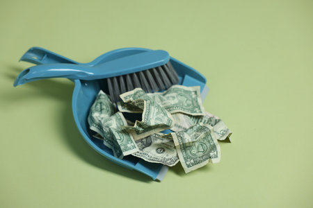 Dollar banknotes, dustpan and broom on green background, closeupの写真素材