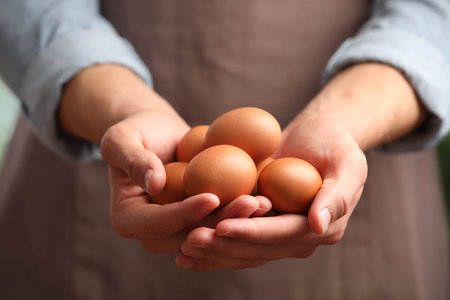 Person with many raw chicken eggs, closeup