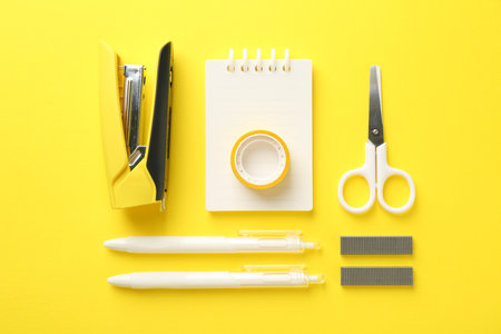 Stapler and other stationery on yellow background, flat layの写真素材