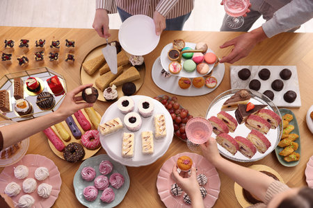 People taking different desserts and drinks from buffet table, above view