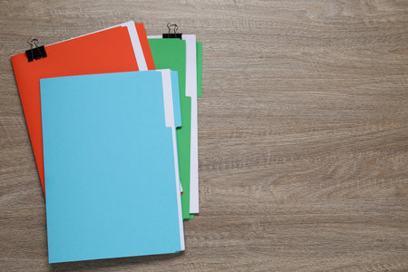 Many documents in folders with binder clips on wooden table, top view. Space for text