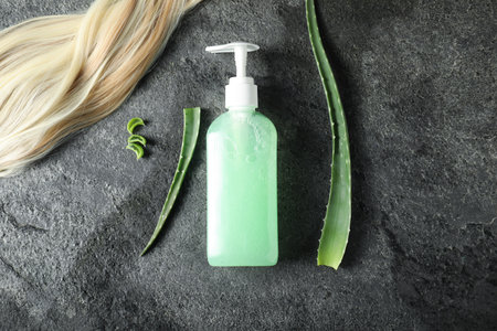 Hair strand, cosmetic product and aloe leaves on gray background, flat layの写真素材