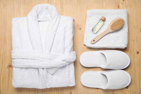 Flat lay composition with bathrobe and spa essentials on wooden background