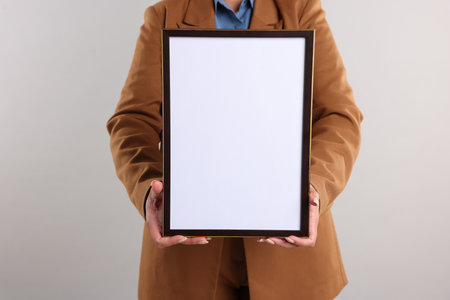 Woman with blank frame on light background, closeup. Mockup for designの写真素材