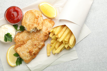 British Traditional Fish and chips served with sauces on light gray table, flat lay. Space for textの写真素材