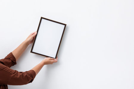 Blank frame on white wall, hanging closeup. Mockup for design