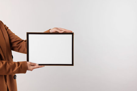Woman with blank frame on light background, closeup. Mockup for designの写真素材