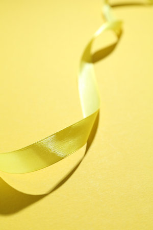 Beautiful ribbon on yellow background, closeup viewの写真素材