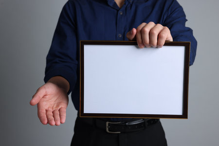 Man with diploma blank frame on light gray background, closeup. Mockup for designの写真素材