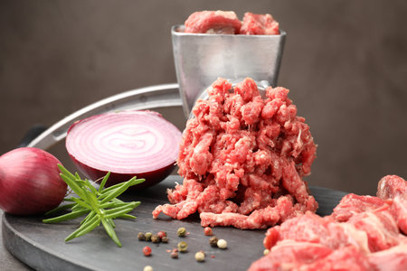 Making minced meat with grinder and spices on gray table, closeup