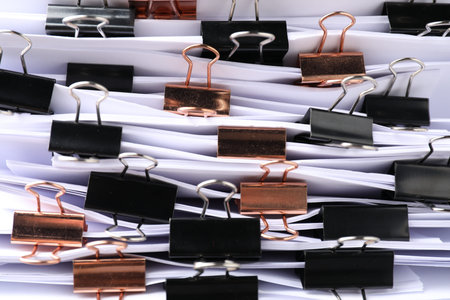 Many documents with binder clips as background, closeup