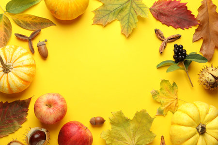Flat lay composition with dry autumn leaves and pumpkins on yellow background. Space for textの写真素材