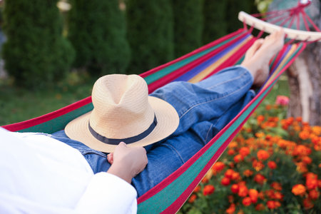 Senior woman with straw hat resting in hammock outdoors, closeupの写真素材