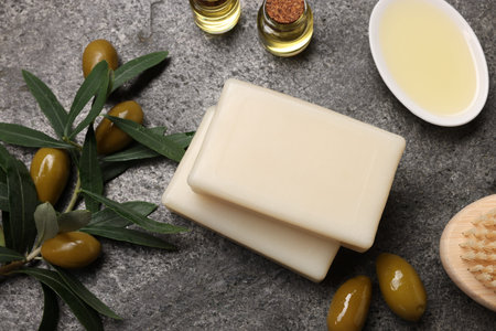 Flat lay composition with handmade soap bars, olives and oil on gray textured tableの写真素材