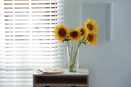 Beautiful sunflowers in vase near window indoorsの写真素材