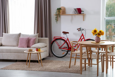 Wooden dining table with chairs, sofa and bicycle in roomの写真素材
