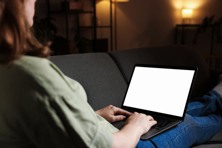 Woman working with laptop on sofa indoors, closeup. Mockup for designの写真素材