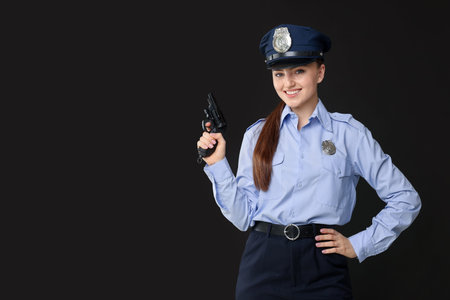 Young policewoman in uniform with gun on black background, space for text