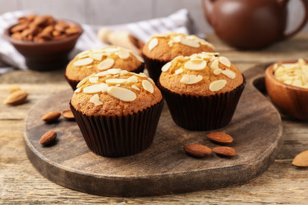 Tasty muffins with almond flakes and nuts on wooden table, closeupの写真素材
