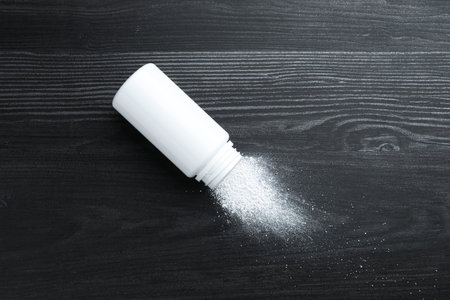 Container with talcum powder on black wooden table, top view. Space for textの写真素材