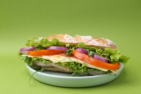 Delicious sandwich with prosciutto, cheese and vegetables on green background, closeup