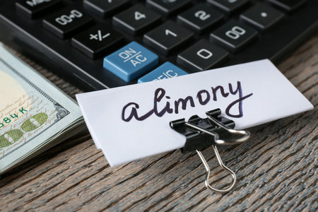 Note with word Alimony, money and calculator on wooden table, closeupの写真素材