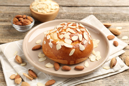 Tasty roll bun with almond flakes and nuts on wooden table, closeupの写真素材