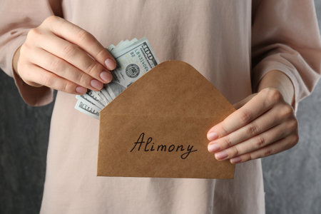 Alimony. Woman taking money from envelope on gray background, closeupの写真素材