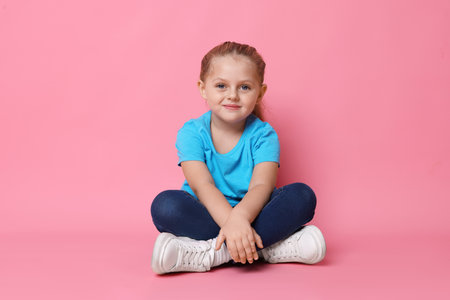 Cute little girl posing on pink backgroundの写真素材