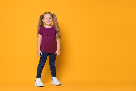 Smiling little girl on orange background. Space for textの写真素材