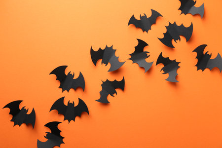 Halloween decor. Black paper bats on orange background, flat layの写真素材
