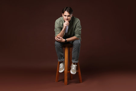 Man on stool against brown backgroundの写真素材