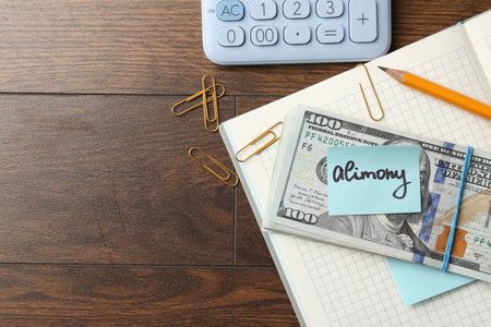 Note with word Alimony, money, notebook, pencil, clips and calculator on wooden table, flat lay. Space for textの写真素材