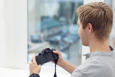 Professional photographer with camera near window in studioの写真素材