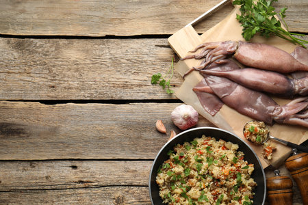 Raw squids, stuffing and parsley on wooden table, flat lay. Space for textの写真素材