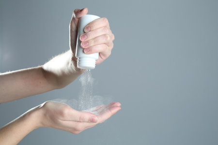 Woman with talcum powder on gray background, closeup. Space for textの写真素材
